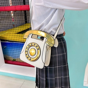 Retro telephone style white crossbody bag with gold handset handle worn by a model