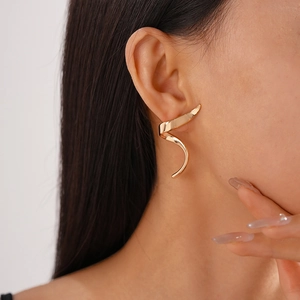 Detailed close-up of a model wearing a gold spiral earring with a modern geometric design