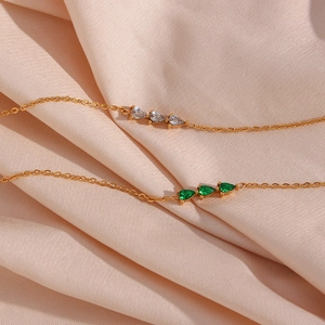 Detail of 18K gold-plated bamboo link necklace with emerald and white teardrop stones