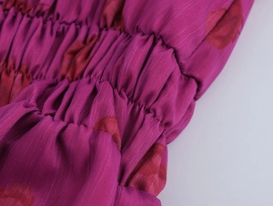 Détail macro du tissu plissé en mousseline fuchsia avec motifs floraux et textures