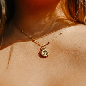 Elegant gold nautilus shell pendant necklace on sun-kissed skin close-up detail