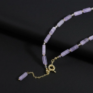 Amethyst beaded necklace with golden clasp and long cylindrical purple stones on black