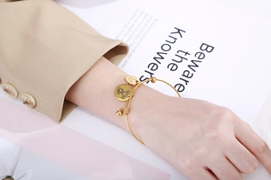 Close-up of golden adjustable bracelet with heart Love charm and circular girl pendant