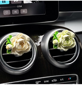 Detail of cream and green jasmine car aroma diffusers on air vent outlet clips