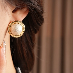 Close-up of vintage French style gold plated round earrings with cotton pearl inlay