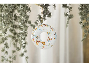 Detail of snowflake donut Christmas resin ornament with colorful beads on a tree branch