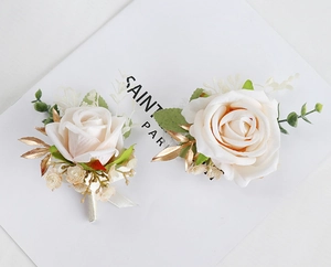 Detail of cream white silk rose corsage with golden leaves and ribbon for weddings