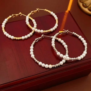 Detail of beaded pearl hoop earrings in gold and silver finish on a luxury wooden jewelry box