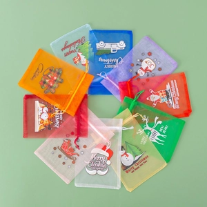 Colorful organza Christmas drawstring bags with festive prints on green background
