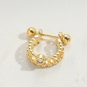 Macro detail of golden U-shaped stud with bead texture and sparkling zircon stones