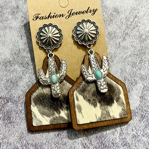 Detail of western bohemian earrings with cactus charm and cow print leather texture