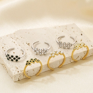 Detailed shot of pearl and emerald rhinestone rings on stone surface in gold and silver