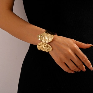 Detailed view of wide gold open cuff with irregular hammered texture and metallic sheen