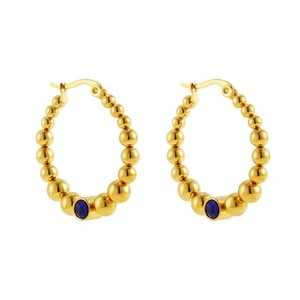 Detailed view of C-shaped gold-plated hoop earrings with blue gemstones and bead texture