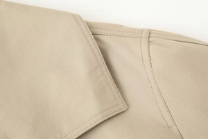 Macro detail of khaki twill fabric with precision double-stitch seams on a trench coat