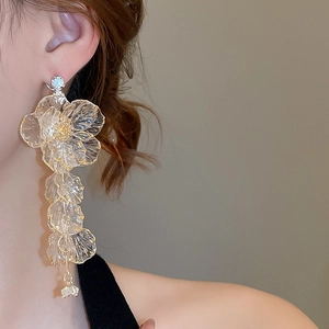 Side view of model wearing transparent acrylic flower earrings with gold tassel details