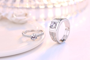 Macro shot of silver six-claw couple rings with round zircons and geometric pattern