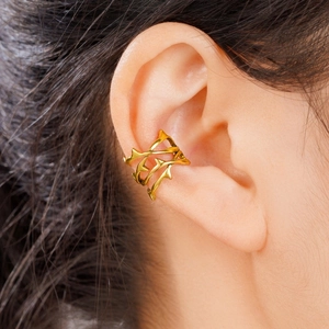 Dettaglio ravvicinato di un earcuff dorato a forma di spina sull'orecchio stile punk