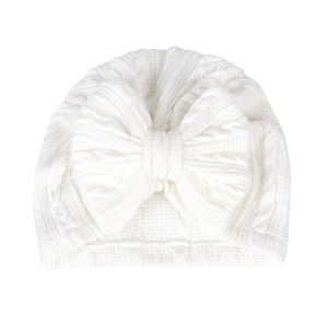 Détail du bonnet turban blanc pour bébé avec gros nœud et motif en maille torsadée
