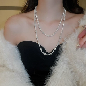 Close-up of double-layer cream pearl necklace styled with elegant white feather coat