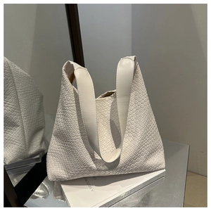 Detail of white woven faux leather bucket bag with wide handle on a mirror tray