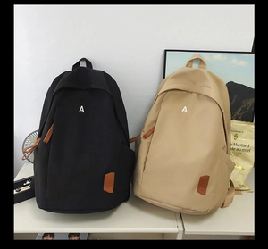 Detailed view of black and beige school backpacks with letter A embroidery on shelves