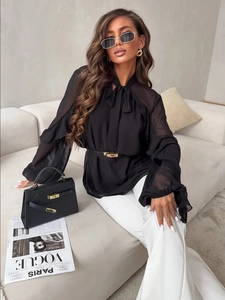 Detail of sheer black chiffon blouse featuring vertical ruffles and elegant bow tie neckline