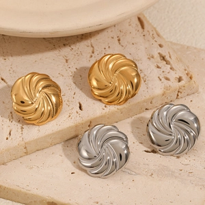 Minimalist 18k gold and silver stainless steel swirl button earrings on beige stone
