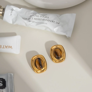 Detailed close-up of vintage gold titanium steel earrings inlaid with brown tiger eye stone