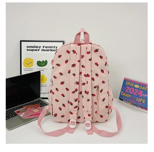 Detail view of pink corduroy backpack with strawberry pattern against a desktop background