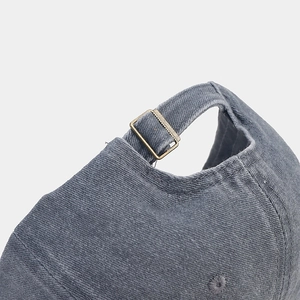 Detail of washed cotton baseball cap featuring vintage bronze buckle and adjustable strap