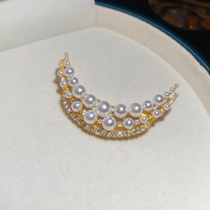 Detail of 18k gold crescent brooch with white pearls and sparkling cubic zirconia stones