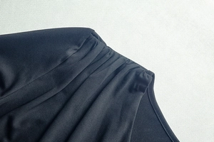 Detail of elegant black slim fit dress showing ruched fabric texture and pleated stitching