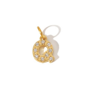 Macro shot of gold-plated letter Q pendant with sparkling zircon inlays on white background