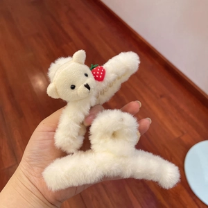 Detailed view of plush hair claws in creamy white with small red strawberry decoration