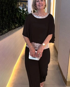 Detail of round neckline and waist with silver sequins on a black loose-fit jumpsuit