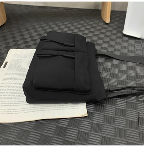 Close-up of black nylon crossbody bag with dual zippered pockets and long drawstring pulls