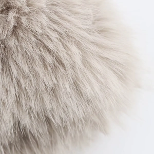 Macro shot of faux fur texture showing soft fluffy fibers in light beige on short coat
