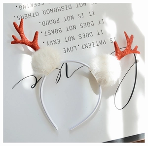 Close-up of sparkling red glitter antlers and white plush pom poms on Christmas headband