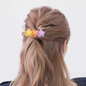 Handmade resin star hair clips in yellow orange and purple colors worn on long hair