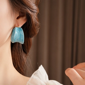 Detail of blue marble resin hoop earring worn by a model in a vintage French style