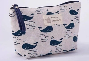 Detail of beige canvas makeup bag with blue whale pattern and durable wrist strap