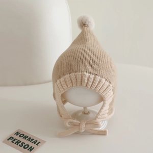 Detail of baby knitted pointed hat with earflaps and bicolor contrast stitching design
