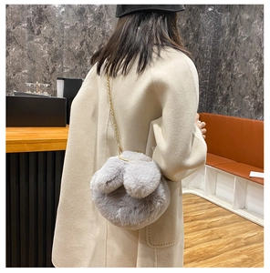 Detailed back view of a grey faux fur rabbit ear handbag with a gold chain strap