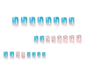 Detail of blue glitter gradient press-on nails with floral patterns and gold foil