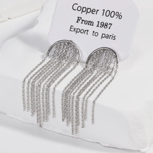 Detailed macro view of silver long tassel earrings with curved metal arc on copper base