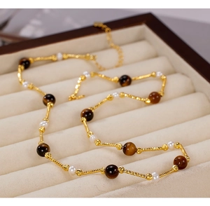 Detail showing natural brown tiger eye stone and small pearls on a golden rope chain