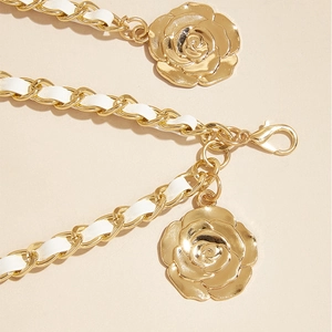 Détail de la ceinture chaîne dorée avec cuir blanc tressé et pendentifs roses