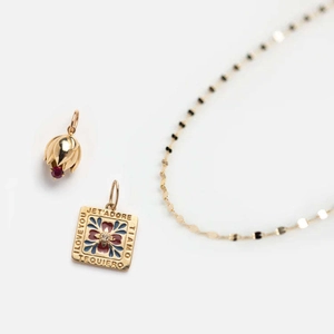 Detailed macro view of gold flower necklace with red gemstone and engraved pendants