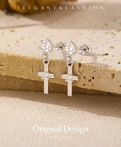 Macro view of silver cross earrings with shimmering zircon inlays on stone texture